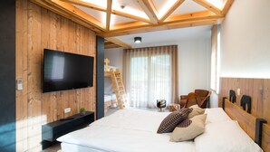 A bedroom with a large bed, wooden walls, a mounted TV, and a ladder against the wall. - Penzion Pr Anzl (Bled)