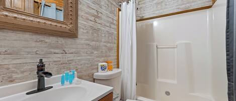 A bathroom with a wooden wall, a white sink, a toilet, and a bathtub.