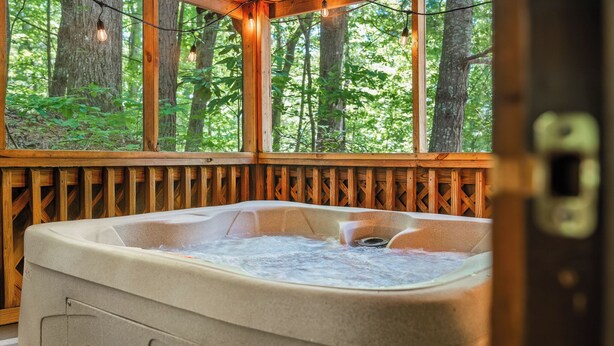 Un jacuzzi con una terraza de madera y vistas a un bosque.