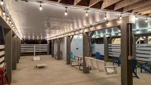 An indoor covered area with benches, tables, and string lights.