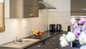 Eine moderne Küche mit Edelstahlgeräten, einer schwarzen Arbeitsplatte und einer Obstschale.