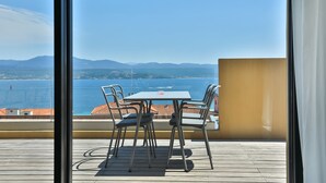 Ein Balkon mit Tisch und Stühlen mit Blick auf die Küste.
