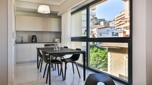 A modern kitchen with a dining area, large windows, and a view of the cityscape. - T2 sea view "Mare e Sole (Ajaccio)