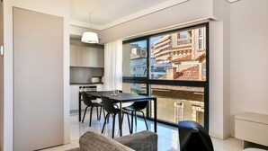 A modern apartment with a dining area, kitchen, and a large window offering a city view. - T2 sea view "Mare e Sole (Ajaccio)