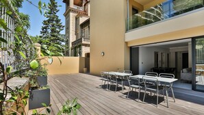 A modern outdoor patio with a wooden deck, white metal chairs, and tables. - T3 large terrace "Sanguinari" (Ajaccio)