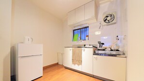 A compact kitchen with a refrigerator, stove, and white cabinets. - Roof Villa Shin-Imamiya (Osaka)