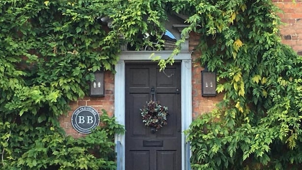 A black door with a wreath, surrounded by ivy and a sign reading "BB". - The Old Stores (Montgomery)