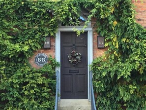 A black door with a wreath, surrounded by ivy and a sign reading "BB". - The Old Stores (Montgomery)