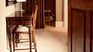 A room with a wooden desk, chair, and a lamp. There is a large mirror on the wall, a wooden door, and a closet with a sliding door. - The Old Stores (Montgomery)