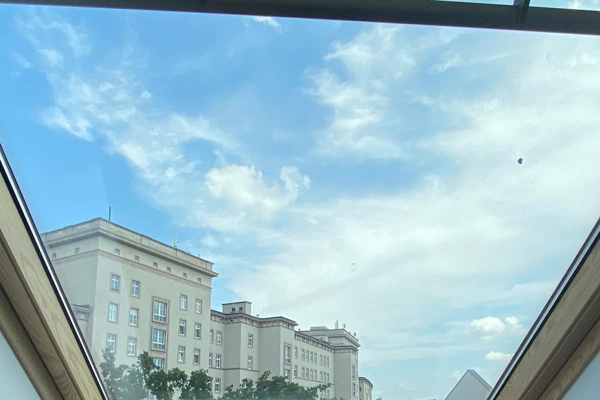 A skylight with a view of a multi-story building and trees.