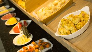 A buffet with various dishes including bread, fruit, and vegetables.