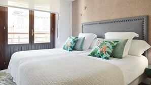 Ett hotellrum med en stor säng, utsikt genom ett fönster och en vägg med ett mönster.