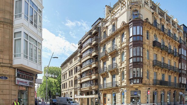 En byggnad med flera våningar i en klassisk arkitektonisk stil, med balkonger och stora fönster.