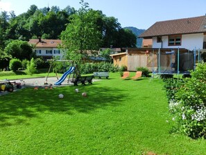 A well-maintained backyard with a play area, including a slide and a swing set.