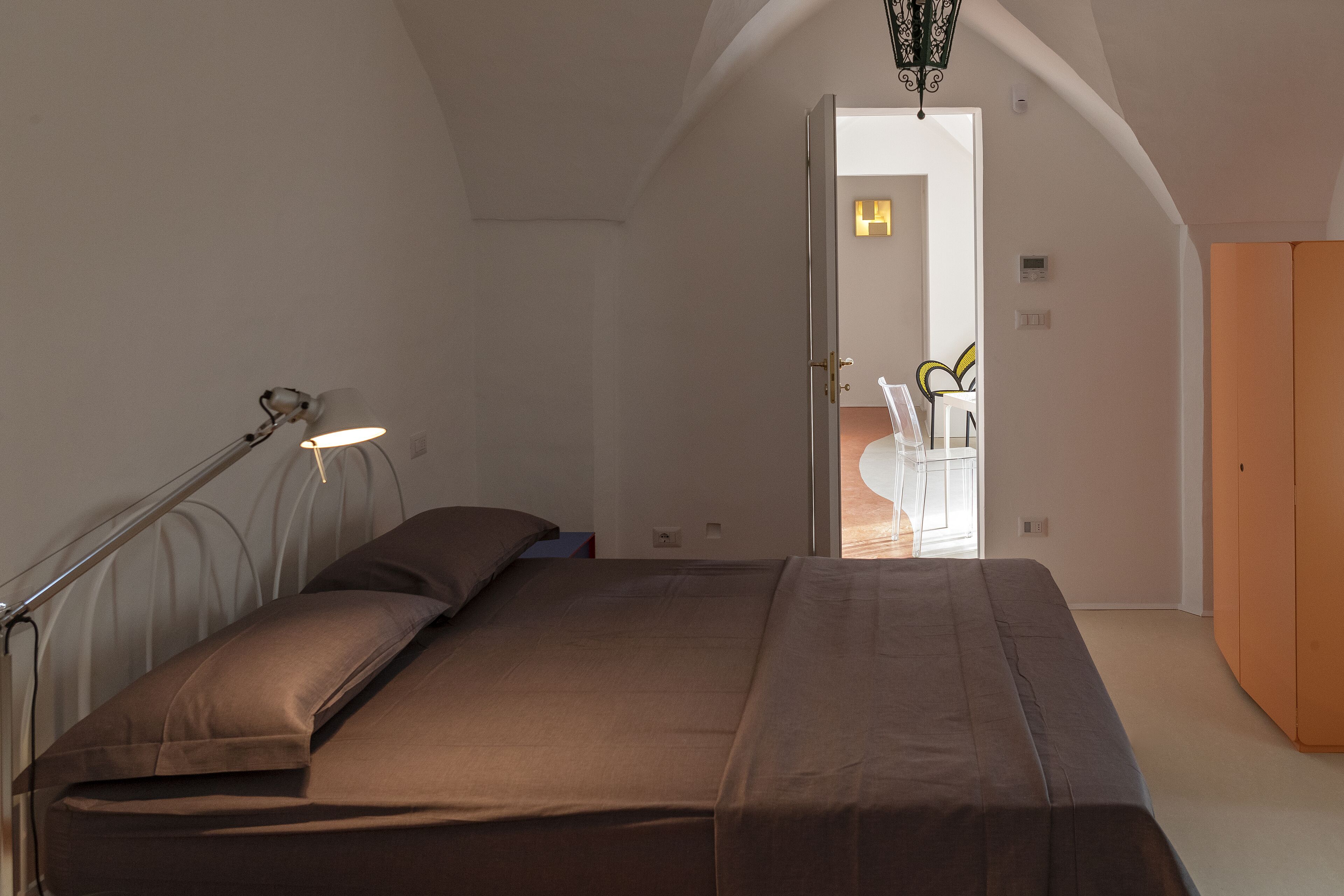 A bedroom with a bed, a bedside lamp, and a wardrobe.