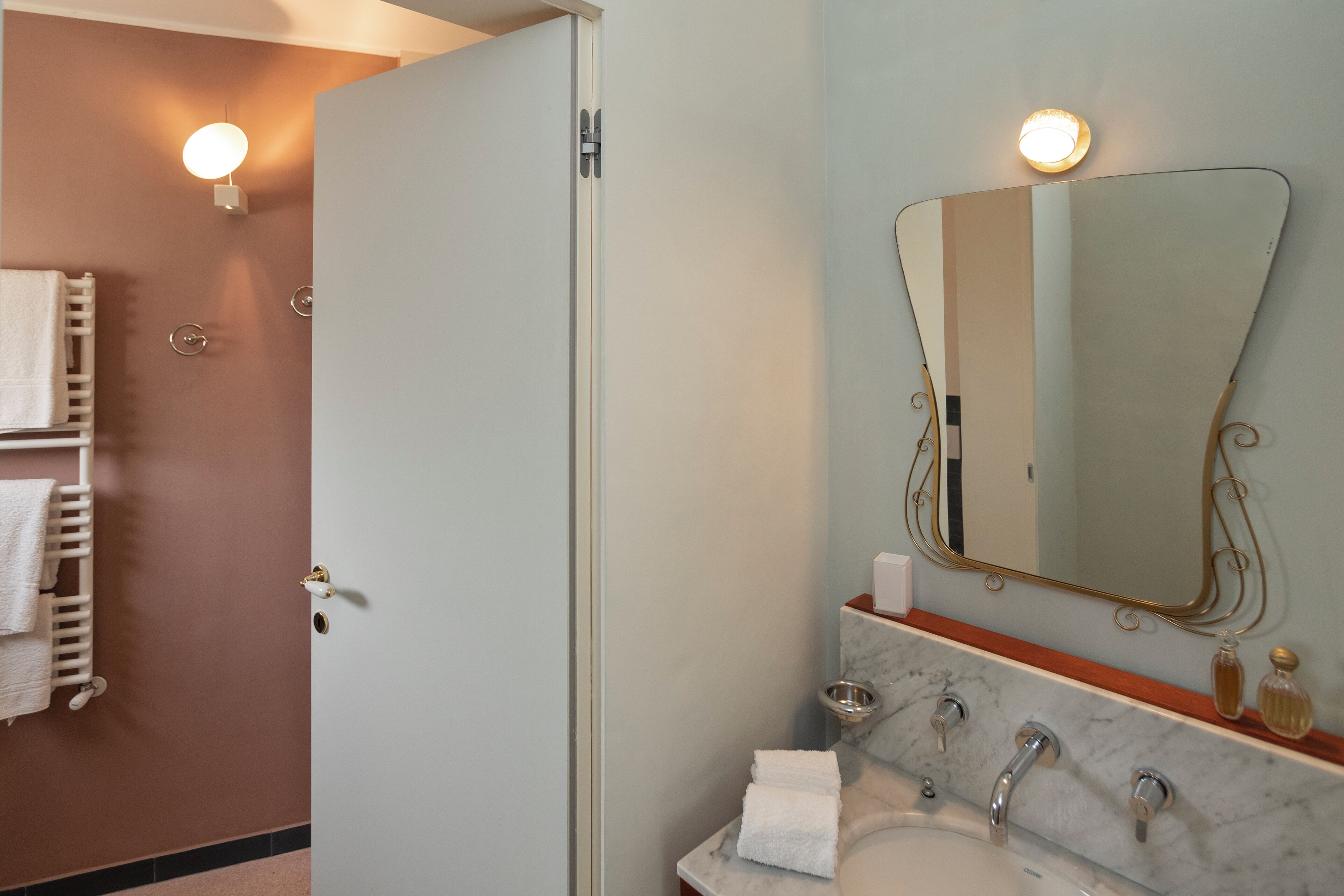 Een badkamer met een marmeren wastafel, een grote spiegel en een handdoekhouder.