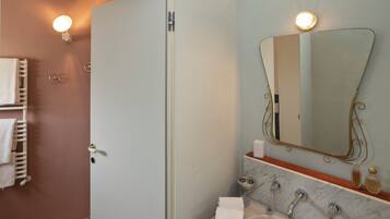 Een badkamer met een marmeren wastafel, een grote spiegel en een handdoekhouder.