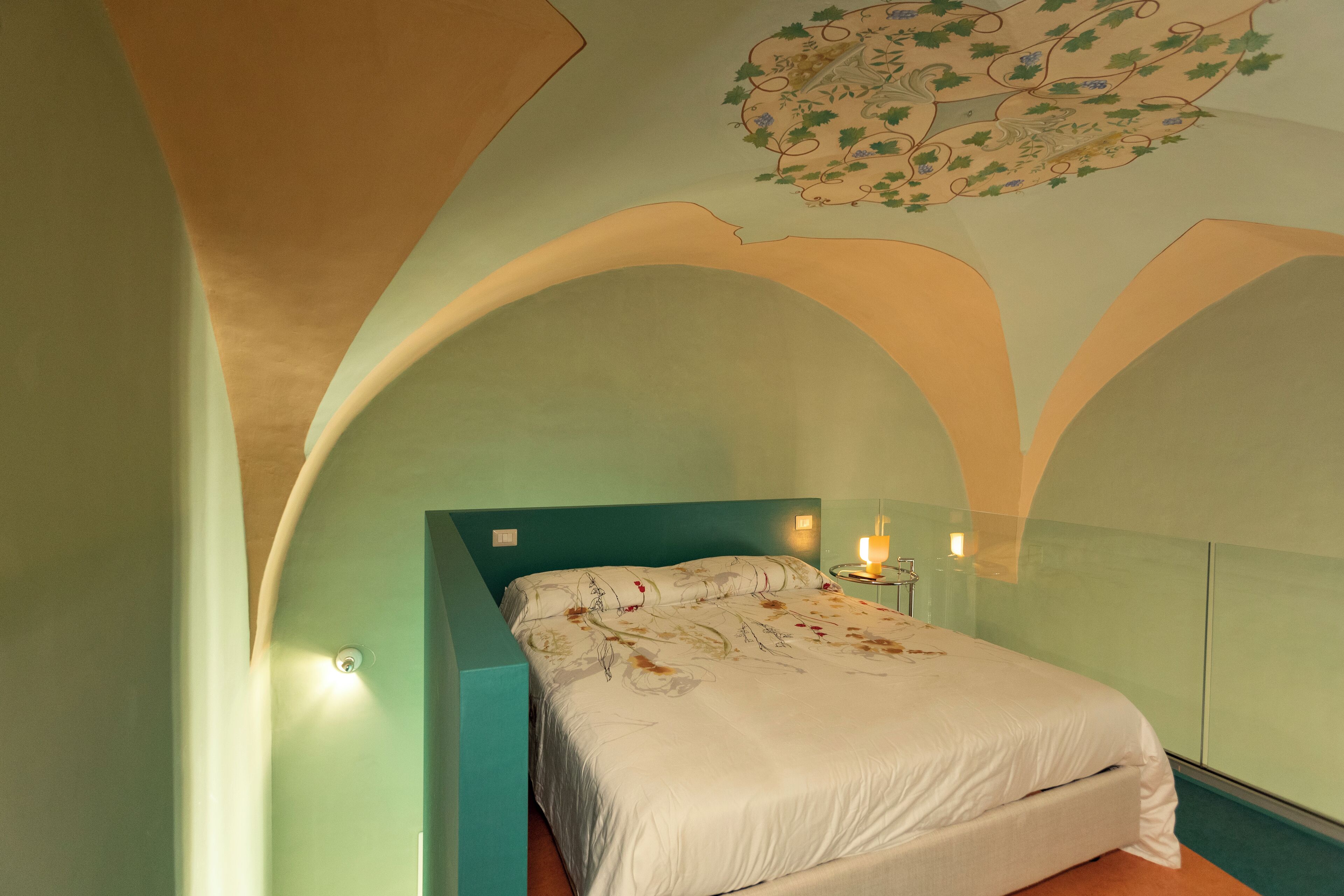 Un dormitorio con cama, mesita de noche y lámpara de pared.