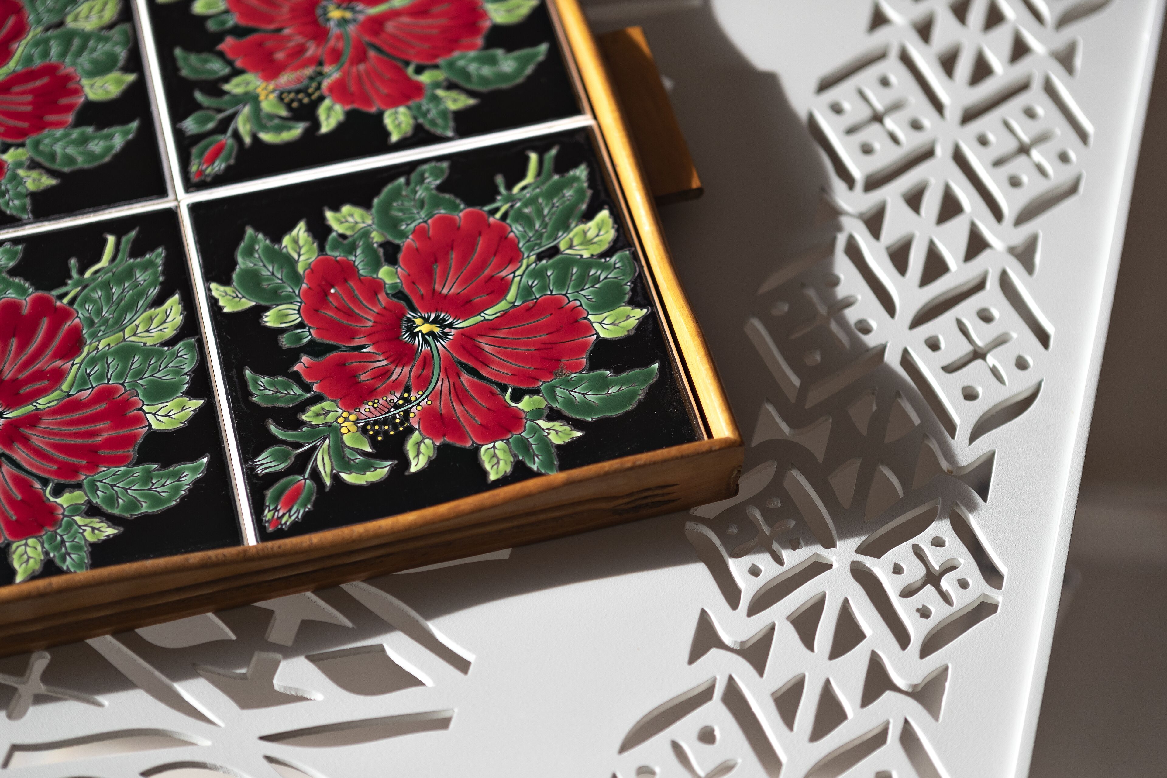 A tiled wall with a floral pattern and geometric cut-out designs.