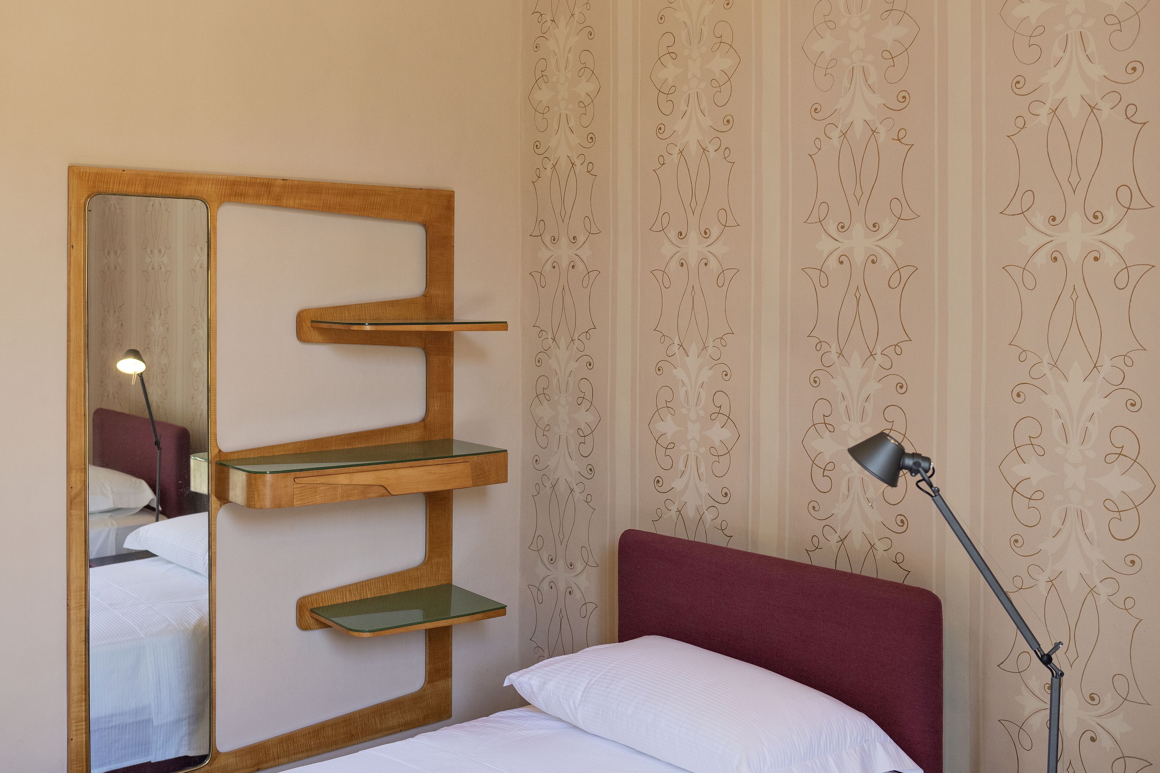 Une chambre à coucher avec une tête de lit en bois, une lampe de chevet et un miroir doté d’étagères.