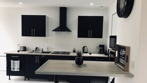 Una cocina moderna con gabinetes negros, una estufa de acero inoxidable y una cafetera.