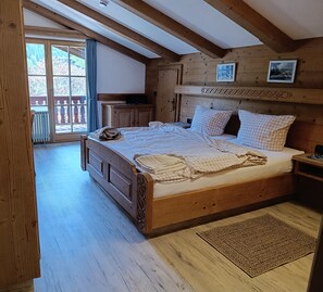 A wooden room with a bed, a window, and a radiator.
