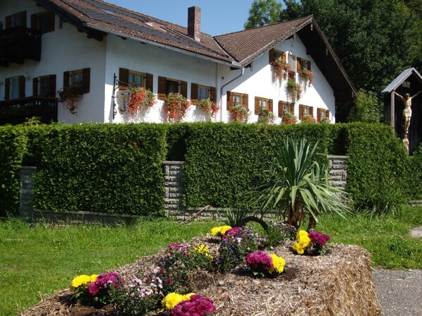 A white house with a sloped roof, wooden shutters, and flower boxes on the windows.