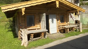Una cabana de fusta rústica amb un porxo, una porta i una finestra.