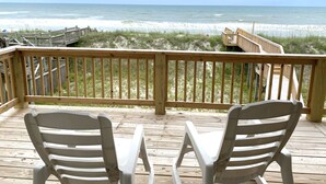 A wooden deck with two white plastic chairs facing a beach with wooden walkways and a boardwalk. - The Surf  - Surf's Up!  Oceanfront  Getaway!!   (North Topsail)