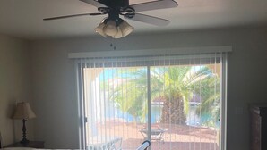 A room with a ceiling fan, a window with blinds, a bed, and a dresser.