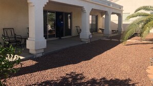 A building with a covered patio area, outdoor seating, and a gravel ground.