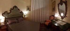 Ett sovrum med en stor säng, en stol, ett bord med en lampa och en spegel.