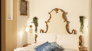 Un letto rifatto con lenzuola a righe, una testiera decorativa e un lampadario a parete.