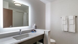 Een moderne badkamer met een grote spiegel, een wastafel en een toilet.