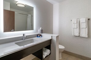 Um banheiro moderno com um espelho grande, uma pia e um vaso sanitário.