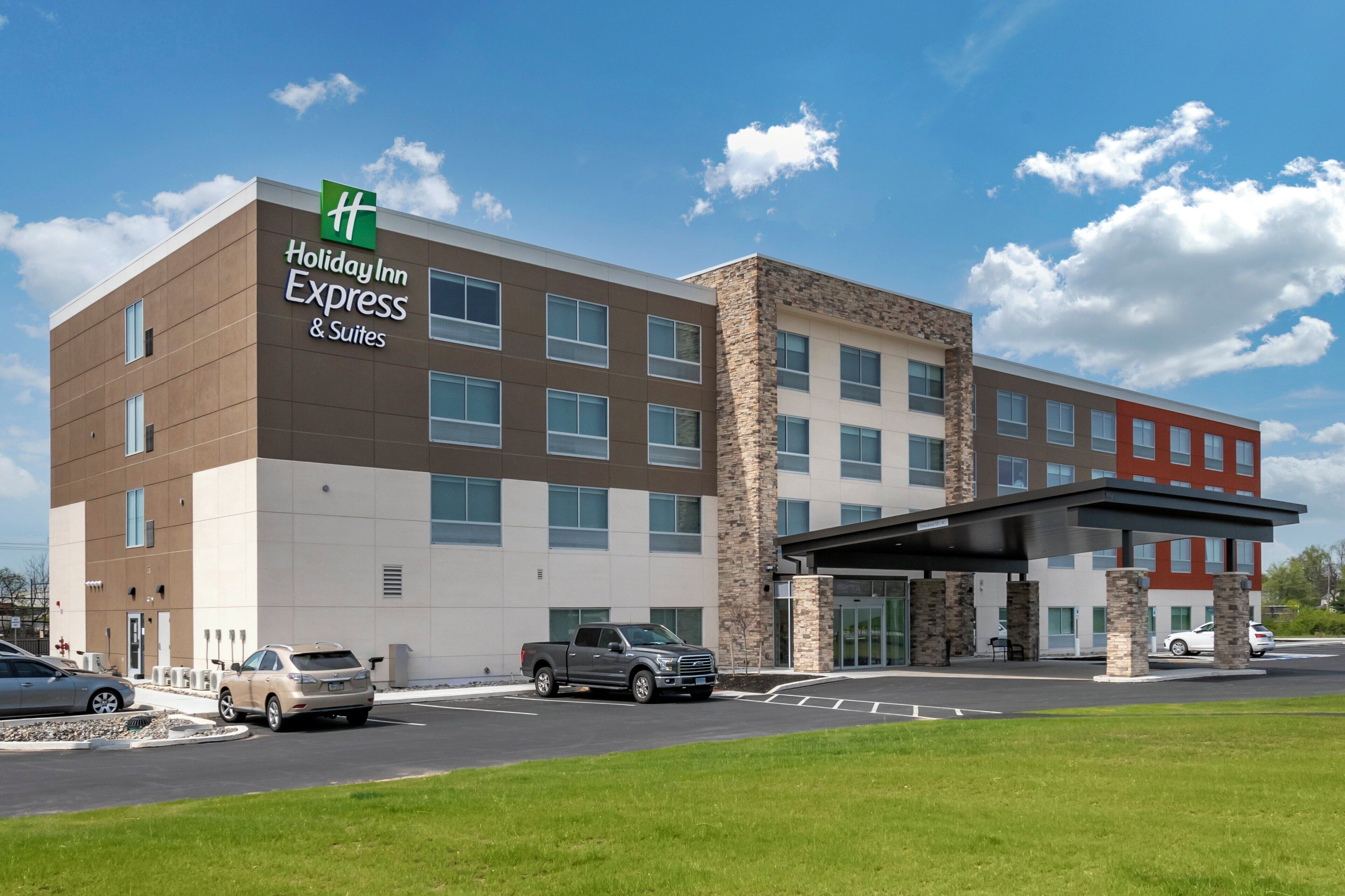 A Holiday Inn Express & Suites building with a modern design, featuring a mix of brick and stone facades, multiple windows, and a covered entrance.