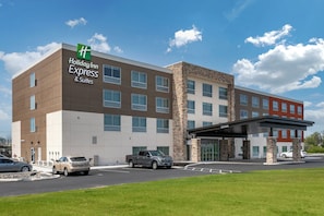 Un bâtiment de la chaîne Holiday Inn Express & Suites, doté d’un design moderne, avec une façade combinant des éléments en brique et en pierre, de nombreuses fenêtres et une entrée abritée.