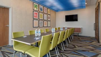 A conference room with a long table, yellow chairs, and framed artwork on the wall.