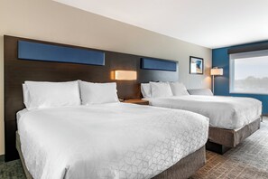Quarto de hotel com duas camas, uma janela grande e vista para o exterior.