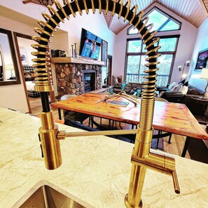 Une cuisine dotée d’une cheminée en pierre, d’une table à manger et d’un robinet de cuisine moderne.