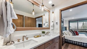 A modern bathroom with a large mirror, dual sinks, and a wooden vanity. - Snowloft Ski In & Ski out (Beaver Creek)