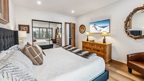 A bedroom with a large bed, a dresser, a mirror, and a television. - Snowloft Ski In & Ski out (Beaver Creek)