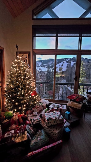 A Christmas tree with lights and presents in a room with large windows overlooking a snowy landscape. - BRAND NEW DESIGNER .  Direct True SKI IN and OUT, 4 Bedroom.  BEST VIEWS!!! (Beaver Creek)
