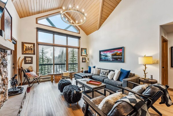 A spacious living room with a large window, a chandelier, and a cozy seating area. - Snowloft Ski In & Ski out (Beaver Creek)
