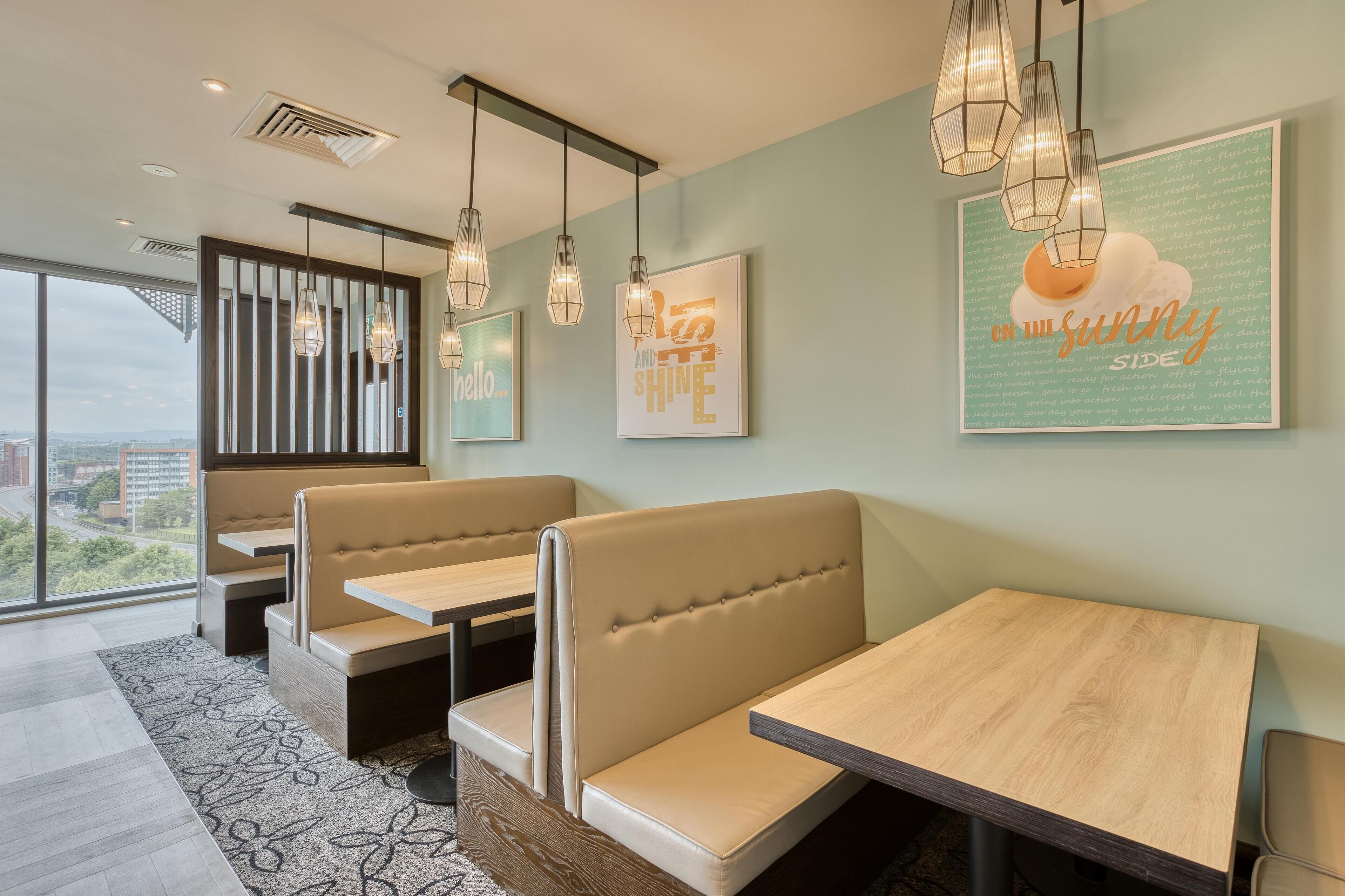 A modern interior with seating, pendant lights, and motivational wall art.