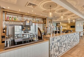 A bar area with a coffee machine, shelves with bottles, and a patterned tile backsplash. - Premier Inn Manchester Cc Princess Street (Manchester)