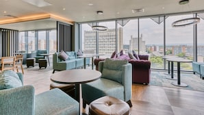 A modern lounge with seating, tables, and large windows offering city views. - Premier Inn Manchester Cc Princess Street (Manchester)