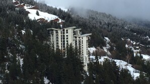 A multi-story building surrounded by snow-covered trees and a mountainous landscape.