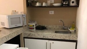 Eine kleine Küche mit Mikrowelle, Kaffeemaschine und einem Kühlschrank.