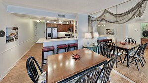 Una cocina compacta con electrodomésticos modernos, un comedor con mobiliario de madera y una original decoración con una red colgante.